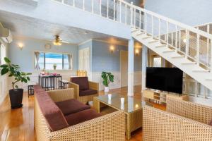 a living room with a staircase and a television at 最大12名 沖縄アリーナ近く アメリカンビレッジまで車で10分 White Terrace in Okinawa City