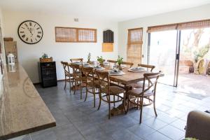 a dining room with a table and chairs and a clock at 87 Sand Street - Buffels bay in Buffelsbaai