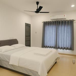 a bedroom with a white bed and a ceiling fan at The Nest in Trichūr