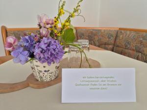 a vase of purple flowers on a table with a sign at Bio-Bauernhof Wilfling in Miesenbach