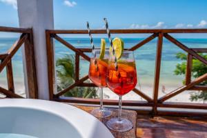 two wine glasses sitting on a table with a view of the beach at ZAN Sun Beach in Makunduchi +61 photos
