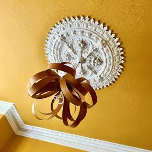 a chandelier with a brown ribbon on a yellow ceiling at Crafnant House - Bed & Breakfast in Trefriw