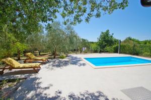 a swimming pool in a yard with two lounge chairs at Holiday house Zara, Pomer in Pomer