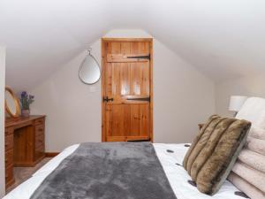 a bedroom with a bed and a wooden cabinet at Church Barn in Holsworthy