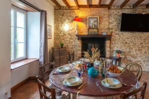 a dining room with a wooden table and a fireplace at Le Chêne des Loges - Campagne - Familial in Bouère