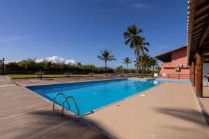 a swimming pool at a resort with palm trees at Apt em Condomínio pé na areia - Praia da Perola in Ilhéus