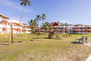 a park with swings and a bench in front of a building at Apt em Condomínio pé na areia - Praia da Perola in Ilhéus