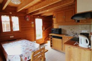 a kitchen with wooden cabinets and a table in a cabin at Chalet des Brimbelles, séjour au cœur de la nature au cœur de la vallée des lacs in Xonrupt-Longemer