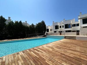 a swimming pool with a wooden deck in front of a building at MARINA 24 by SOM Menorca in Fornells