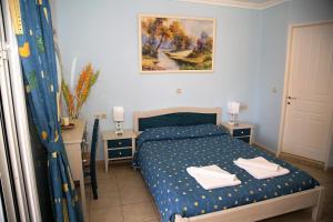 een slaapkamer met een bed en twee tafels en een schilderij bij Helen Apartments & Studios in Agios Stefanos