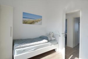 a white bedroom with a bed and a painting on the wall at Ferienwohnung Wilbur Olpenitz in Olpenitz
