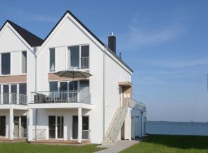 a white house with an umbrella in front of the water at Ferienwohnung Wilbur Olpenitz in Olpenitz +32 photos