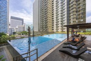a large swimming pool with lounge chairs and buildings at Virgo Nest Rentals - Avida Riala IT Park - City View in Tabok