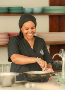 a woman in a kitchen preparing food in a bowl at Casa del Pavo Real Boutique Hotel in Palomino