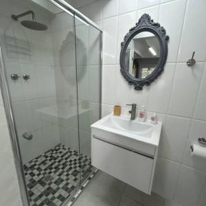 Un baño con ducha, lavabo y espejo. en Our Little Guest House, en Langebaan