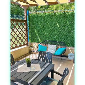 a patio with a table and chairs and a green hedge at Avrora Studio's in Byala