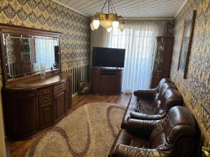 Una sala de estar con un sofá de cuero y un televisor. en Джакузи! Двухкомнатная квартира, Героев Труда Французкий, бульвар,Барабашово, en Járkov