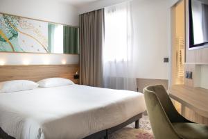 a bedroom with a bed and a desk and a chair at Brit Hotel Angers Parc Expo - L'Acropole in Saint-Sylvain-dʼAnjou