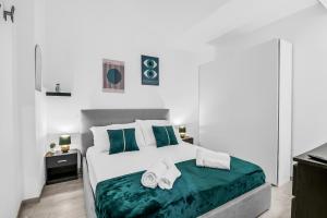 a bedroom with a white bed with green sheets and slippers at Luxury House Jacuzzi - Milano in Milan