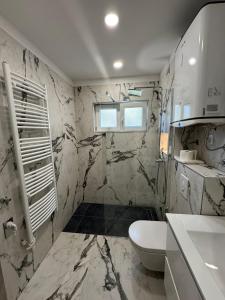 a bathroom with marble walls and a toilet and a sink at Apartments Peričić in Podstrana +53 photos