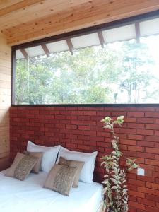 a bed in a brick wall with a window at The Palace Eco Cottage in Ella