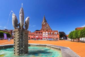 a statue in a fountain in front of a building at Vinetahotel Stadt Barth in Barth