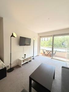 Una sala de estar con un televisor, un sofá y una mesa. en Appartement Brochant Batignolles Paris, en París