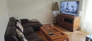 a living room with a black couch and a television at La Meinau in Strasbourg