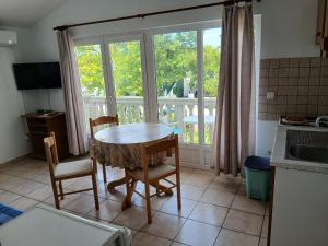 a kitchen with a table and chairs and a balcony at Put Kandelica 86 in Privlaka