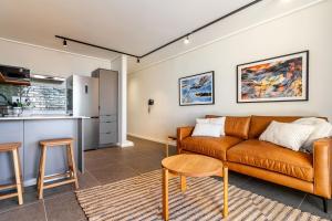 Una sala de estar con un sofá y una cocina. en 1-Bedroom Ocean-View Apartment Wavescapes, Muizenberg Beach, en Muizenberg
