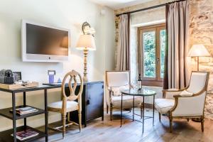 a living room with a desk and chairs and a tv at Grand Hotel Don Gregorio in Salamanca