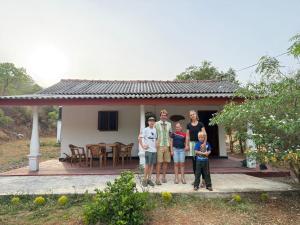a family standing in front of a small house at Hena Villas in Kataragama
