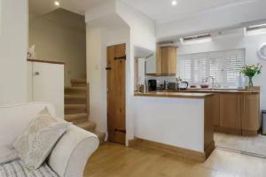 eine Küche und ein Wohnzimmer mit einem Sofa und einer Theke in der Unterkunft Rogate Cottage Retreat in Petersfield