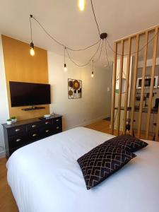 a bedroom with a large white bed with a television at The Brut Case - Avenue de Champagne in Épernay