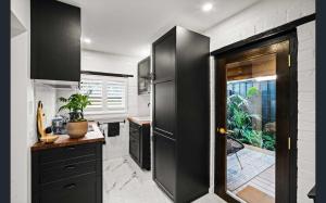 eine Küche mit schwarzen Schränken und einem schwarzen Kühlschrank in der Unterkunft Contemporary Apartment in West Hobart in West Hobart