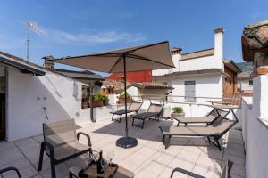 a patio with tables and chairs and an umbrella at Appartamenti del Borgo a 2 passi dal lago, quite in Garda