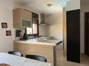 a kitchen with a sink and a counter with chairs at Luminoso y Elegante, piscinas y pistas de pádel in Palm-mar