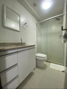 Un baño con inodoro, lavabo y espejo. en Excelente Flat Boa Viagem Andar Alto, en Recife