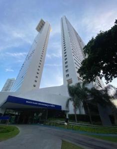 Dos edificios altos con una persona parada frente a ellos. en Excelente Flat Boa Viagem Andar Alto, en Recife