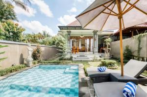 a house with a swimming pool and an umbrella at Puri Trisna in Ubud