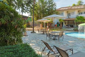 a patio with tables and chairs next to a pool at Pousada Porto do Sol in Pôrto Rico