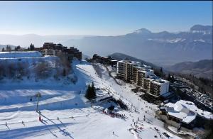 a group of people skiing down a snow covered slope at Le May'hé - Studio Cabine Et Balcon in Les Adrets