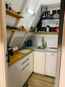 a small kitchen with white cabinets and a sink at Ferienhaus am Waldrand in Billerbeck +3 photos