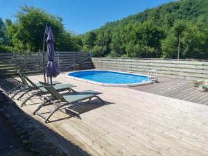 a deck with chairs and an umbrella and a pool at Charmante maison piscine privée in Siorac-en-Périgord