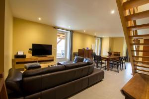 a living room with a leather couch and a television at Charmante maison piscine privée in Siorac-en-Périgord
