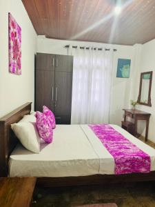 Un dormitorio con una cama grande con almohadas moradas. en Hotel Halona, en Kandy