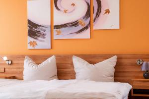 a bed with white pillows and paintings on the wall at Hotel Casa Nostra in Schloß Holte-Stukenbrock