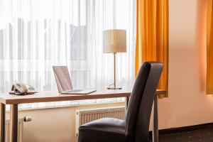 a desk with a laptop and a lamp and a chair at Hotel Casa Nostra in Schloß Holte-Stukenbrock
