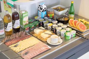 a counter topped with cheese and meats and other foods at Brit Hotel Mâcon Centre Gare in Mâcon