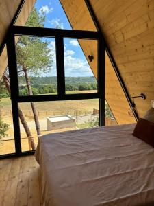 un letto in una camera con una grande finestra di Chalet VercoréA 56 m2 pour 4 personnes au Domaine CollinéA SPA Privatif a Bathernay